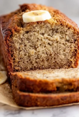 Loaf of easy moist banana bread with slices on a wooden kitchen table