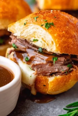 Delicious French Dip Sliders with beef, cheese, and au jus for dipping