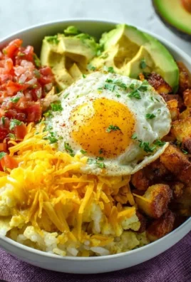 A colorful breakfast burrito bowl filled with eggs, salsa, beans, and avocado.