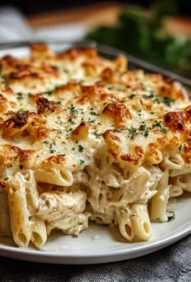 Creamy Chicken Alfredo Pasta Bake topped with cheese and herbs
