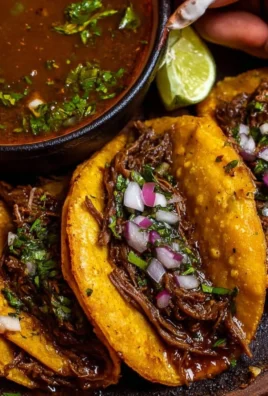 Delicious birria tacos served with rich broth and fresh toppings.