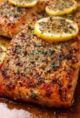 Plate of garlic lemon roasted salmon garnished with herbs and lemon wedges