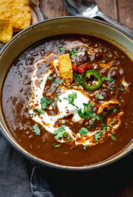 A bowl of Mexican Style Black Bean Soup garnished with cilantro and lime.