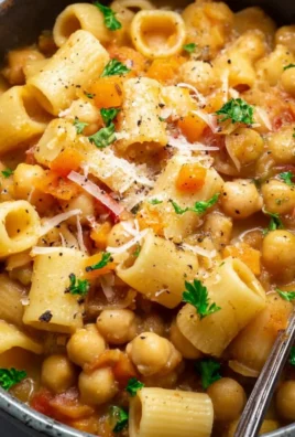 A bowl of pasta with chickpeas garnished with herbs and spices