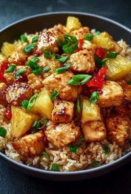 Plate of pineapple chicken served with rice, garnished with fresh herbs.