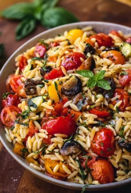 Bowl of roasted vegetable orzo with colorful vegetables and herbs