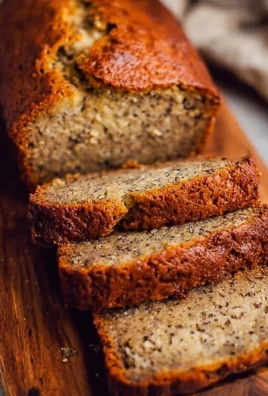 Moist banana bread loaf on a wooden table with banana slices