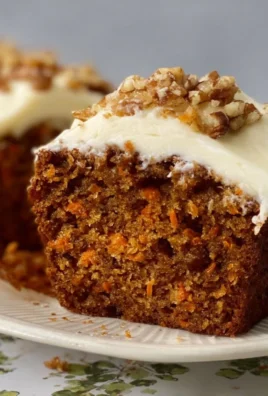 Mini carrot cake loaves topped with cream cheese frosting and garnished with walnuts.