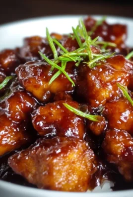 Plate of sticky honey chicken garnished with green onions and sesame seeds