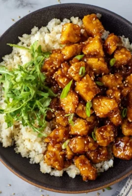 Vegan Orange Chicken made with tofu, garnished with green onions and sesame seeds.