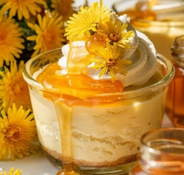 Creamy dandelion honey cheesecake cups topped with fresh herbs and flowers.