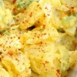 Delicious deviled egg potato salad with creamy dressing and garnishes.