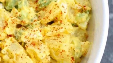 Delicious deviled egg potato salad with creamy dressing and garnishes.