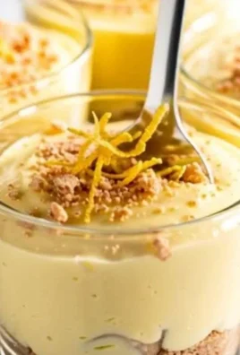 Fresh lemon cheesecake cups garnished with lemon zest and mint leaves