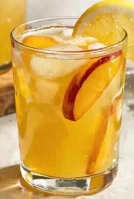 Fresh peach lemonade in a glass with a slice of peach and lemon garnish