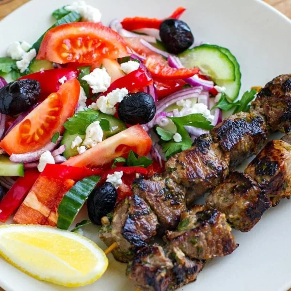 Plate of Greek souvlaki lamb served with a fresh salad
