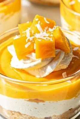 Mango Coconut Cheesecake Cups topped with tropical mango slices and coconut flakes