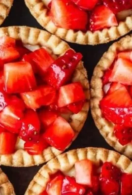 Mini strawberry tartlets topped with fresh strawberries and whipped cream.