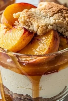 Peach Cobbler Cheesecake Cups served in elegant glassware with fresh peaches