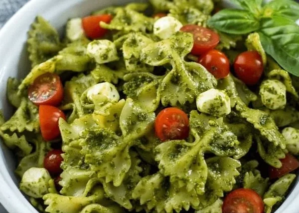 Delicious pesto pasta salad with fresh vegetables and basil