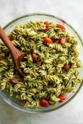 Pesto pasta salad with cherry tomatoes, fresh mozzarella, and basil served in a bowl