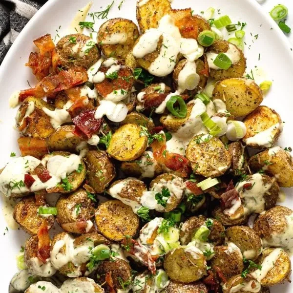 A vibrant bowl of Roasted Potato Salad with colorful vegetables and herbs.