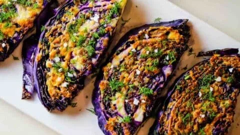 Delicious roasted red cabbage steaks with garlic parmesan topping on a plate.