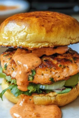 Homemade salmon patties served with fresh herbs and lemon wedges