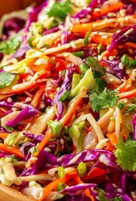 Bowl of simple Asian coleslaw topped with sesame dressing and colorful vegetables.
