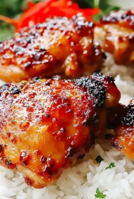 Delicious sticky sweet chili chicken thighs on a plate garnished with herbs