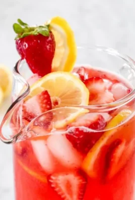 Glass of sweet strawberry lemonade with fresh strawberries and lemon slices