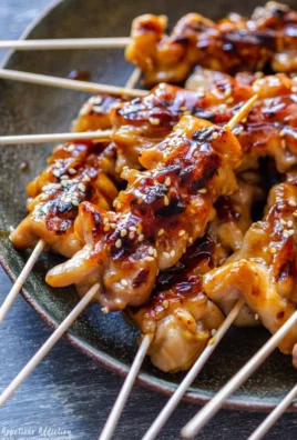 Grilled teriyaki chicken skewers garnished with sesame seeds and green onions