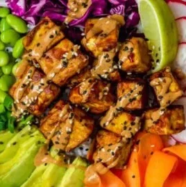 Delicious Tofu Buddha Bowl topped with creamy peanut sauce and fresh vegetables