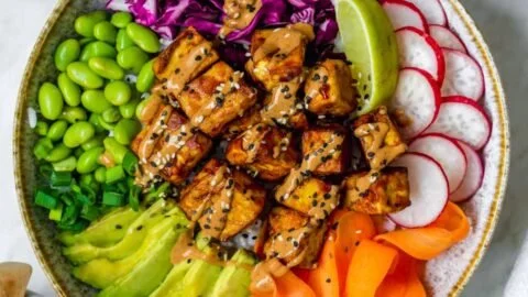Delicious Tofu Buddha Bowl topped with creamy peanut sauce and fresh vegetables