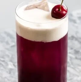 Tropical Cherry Rum cocktail garnished with cherries and fresh fruit.