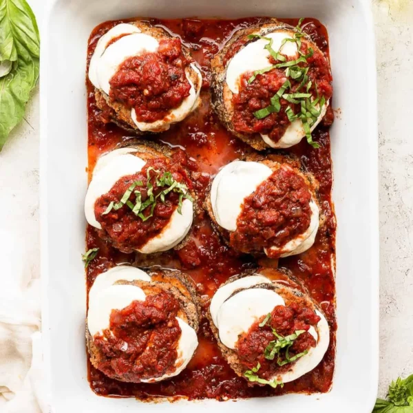 Delicious baked eggplant parmesan topped with cheese and fresh herbs