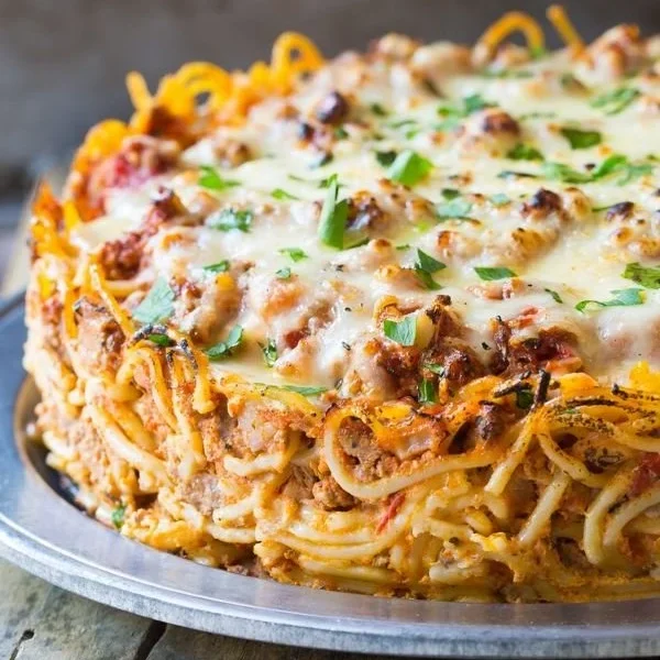 Cozy baked spaghetti pie with melted cheese and herbs in a rustic dish