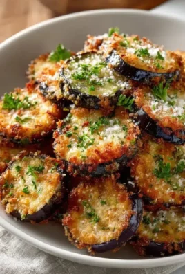 Crispy skillet fried eggplant slices on a plate, garnished with herbs
