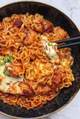 Fiery chicken noodles served in a bowl with fresh veggies and spices.