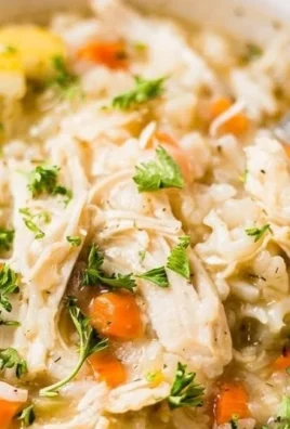 Bowl of Greek lemon chicken soup with fresh herbs and lemon slices