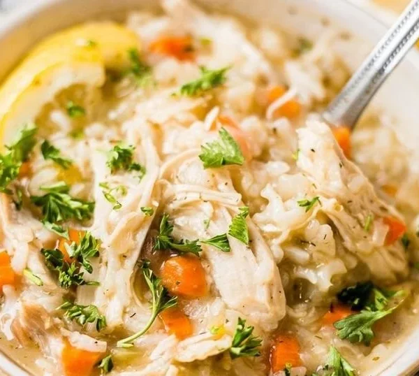 Bowl of Greek lemon chicken soup with fresh herbs and lemon slices