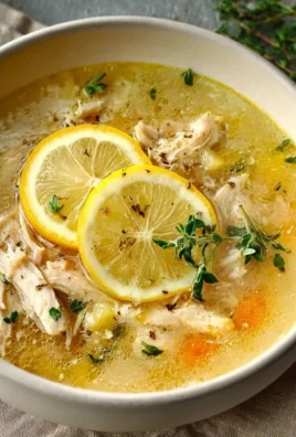 Bowl of Greek lemon chicken soup garnished with fresh herbs and lemon slices