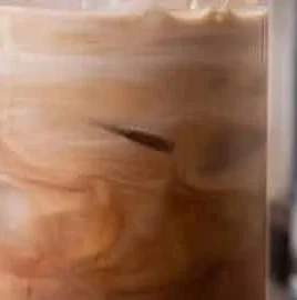 Homemade iced mocha coffee in a glass with whipped cream and chocolate drizzle.