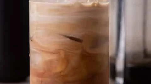 Homemade iced mocha coffee in a glass with whipped cream and chocolate drizzle.