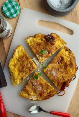 Delicious leftover pasta frittata garnished with herbs on a white plate.