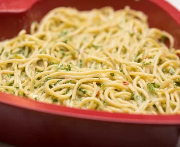Delicious leftover pasta frittata served on a plate with fresh herbs.