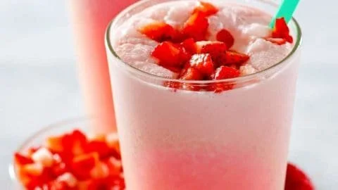 Starbucks Pink Drink in a clear cup with strawberries and coconut milk